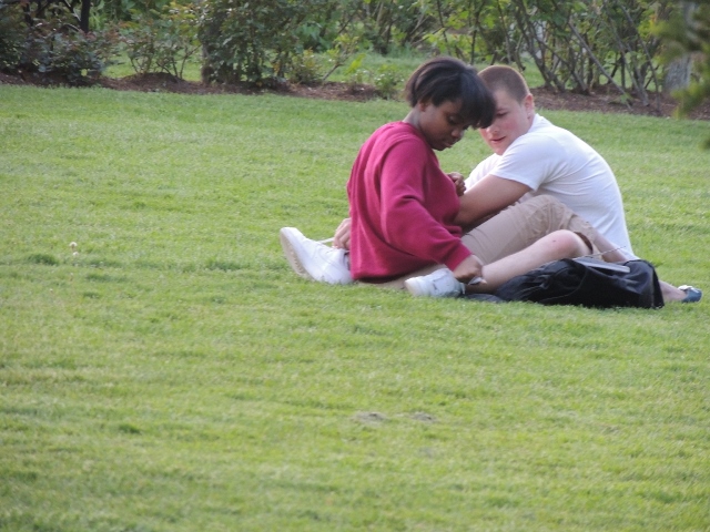 young interracial couple sitting on grass,love display